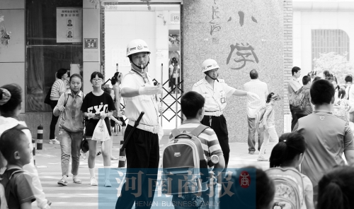 伊河路小學(xué)門口，兩名巡防隊(duì)員護(hù)送學(xué)生過(guò)馬路