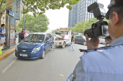 在金水路，交警對在機(jī)動車道違法停放的車輛施行拖離