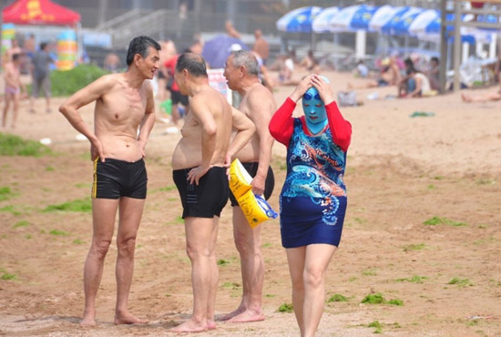 2013年7月3日，山東青島青島高溫來襲，“青島大媽”不懼滸苔，戴著“強盜面具”出現在海水浴場消暑降