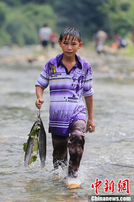 圖為7月9日，一名男孩在鬧魚節(jié)活動(dòng)中抓到了兩條魚。譚凱興 攝