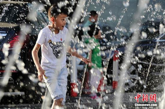 山西太原最高溫36℃,兒童在噴泉周圍戲水消暑。