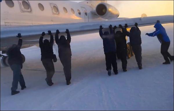 伊加爾市一架客機起飛前被凍在了跑道上。飛機上的乘客不得不下來推飛機。