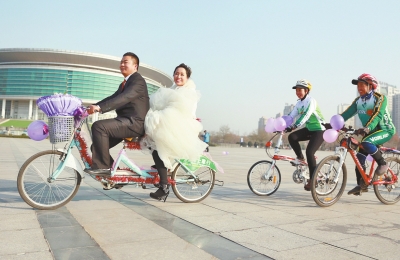 氣球和鮮花裝點(diǎn)的雙人自行車，新郎郝幸福載著美麗新娘回家。