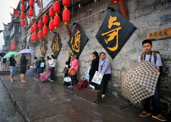 　4月29日上午11時(shí)20分，一些游客和古城當(dāng)?shù)氐木用穸阍谝粋€(gè)酒吧的屋檐下避雨。這些當(dāng)?shù)鼐用褚詾橛慰团恼罩\生，一場(chǎng)降雨讓他們的生意更加清淡。
