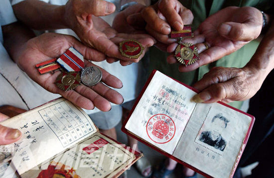 幾位志愿軍老兵展示自己的立功證、傷殘軍人證與勛章