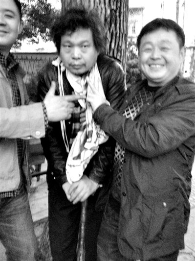 兩名接訪人員與患有癌癥的訪民段新德合影時，面帶笑容擺出勝利的手勢。