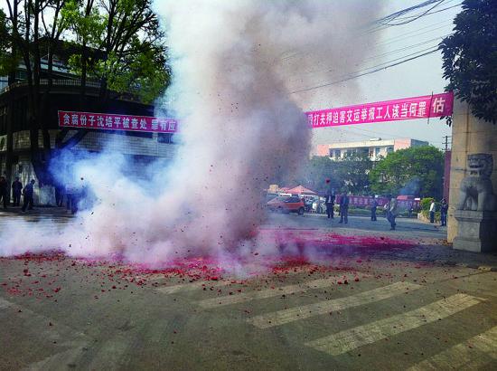 市民在普洱市主干道振興大道的金孔雀交通運(yùn)輸集團(tuán)有限公司門(mén)前燃放鞭炮，公司門(mén)前掛著“貪腐份子沈培平被查處，罪有應(yīng)得，大快人心?！钡臈l幅