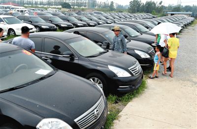 昨日，市民在山東棗莊一家拍賣公司場地上查看待拍賣公車。當(dāng)日，棗莊市103輛公車公開拍賣。新華社記者