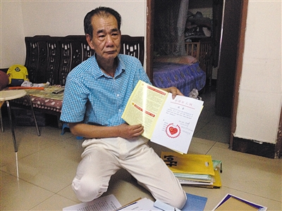 翻出一家網(wǎng)站贈予的“中國好人”證書，區(qū)少坤單膝跪在地上，“你看，我是中國好人啊?！?范春旭 攝