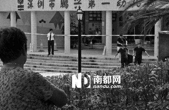 →7月19日，鵬興花園第一幼兒園門前，民警在現(xiàn)場進行完勘查取證后，園長和保安的尸體被運走。南都記者 徐文閣 攝
