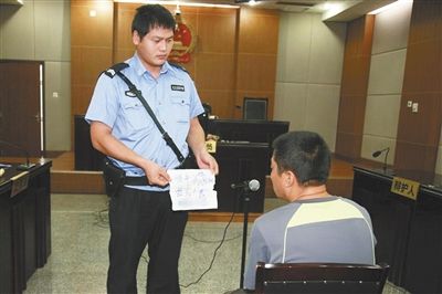 昨日庭審中，法警向趙某出示其扎完車胎后所留辱罵公司的紙條。通訊員 李秀文 攝