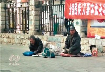 工人體育場北路，兩位乞討者路邊乞討，并輪流扮成“病人”（躺地者）。 央視截圖