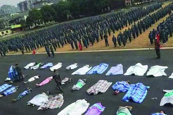 20多名女生躺在瀝青跑道上，身上嚴(yán)嚴(yán)實(shí)實(shí)地裹著棉被，接受太陽的照曬。