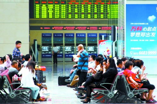 候車大廳溫度很高，一名乘客一手扇風、一手擦汗