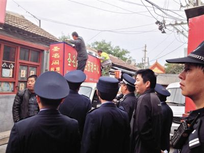 昨日下午,東城區(qū)工商、城管、公安等部門,對(duì)雍和宮附近的預(yù)測(cè)中心進(jìn)行清理整頓,站在車頂?shù)膬擅と苏鸪患摇邦A(yù)測(cè)中心”的招牌。因雍和宮、白云觀等文化景點(diǎn)外聚集大量算命先生,被媒體稱為“算命一條街”。本版攝影/新京報(bào)記者 李寧 攝