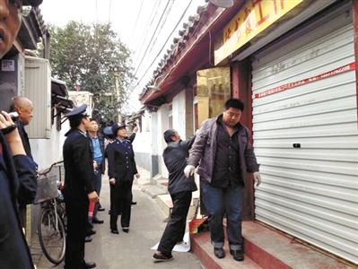 執(zhí)法人員拆除胡同里一家店面未經(jīng)審批的招牌。