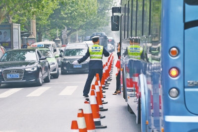 省人民醫(yī)院南門(mén)的路中間擺放反光錐，交警示意由西向東車(chē)輛從前方繞行。