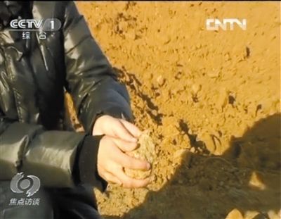 麻剛沙系麻剛石粉碎而成。記者找到一塊麻剛石，一捏就碎成粉末，硬度非常差。央視截圖