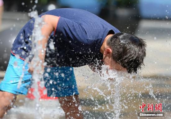 5月29日，一名小孩將頭伸向北京街頭的噴泉以降溫祛暑。
