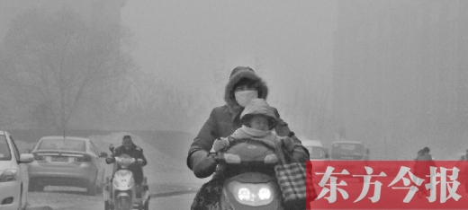 12月8日，鄭州市未來路上，一位市民帶著孩子在霧中騎行