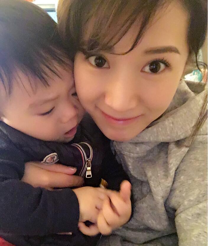 照片中李念狂吻兒子，小寶貝自顧自地玩著。