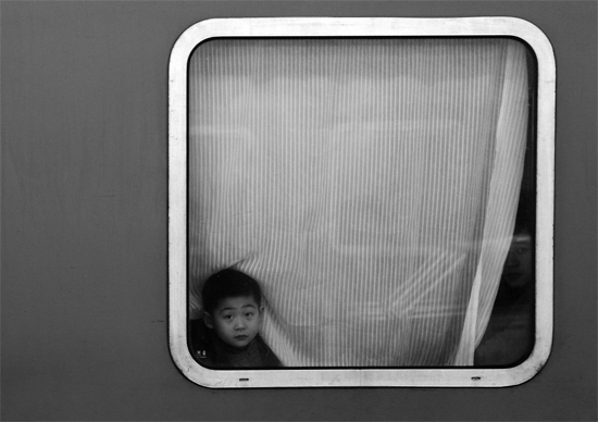 一個(gè)孩子把頭伸向窗外，他想再看送別的親人一眼
