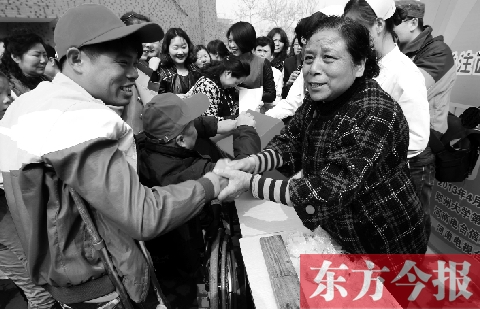 昨日，鄭大四附院的大樓前，“面人鄭”鄭玉芬（右）向前來捐款的殘疾人表示感謝