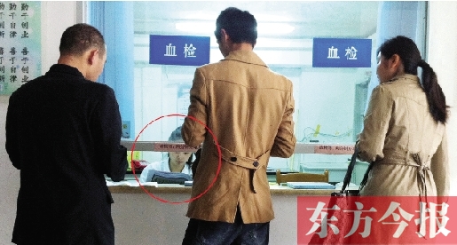 昨日，鄭州市二七區(qū)疾控中心辦證大廳，血檢窗口內(nèi)一名女工作人員，邊接受辦證者咨詢邊看報紙