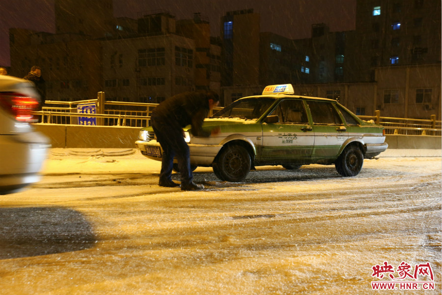 一位出租車司機(jī)在車輪前灑上雪，希望能增加輪胎的摩擦力。