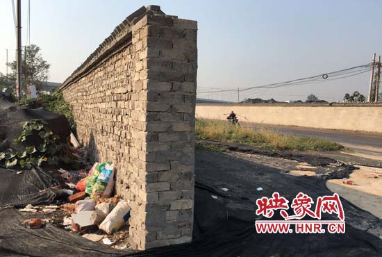 一墻之隔，一邊是道路，一邊是垃圾和荒草，市民質(zhì)疑其為遮羞墻。