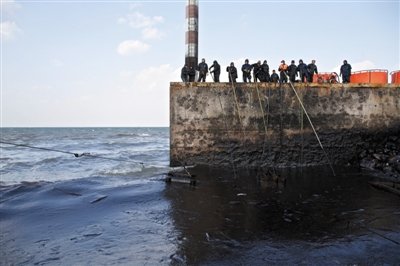 昨日，山東青島，清污人員正在海邊清理油污。