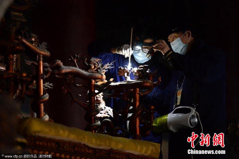圖為工作人員使用軟毛刷和吸塵器對太和殿的金漆雕龍寶座除塵。