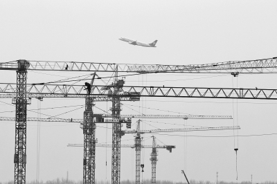 空中是起飛的飛機(jī)，下面是T2航站樓工地上林立的塔吊
