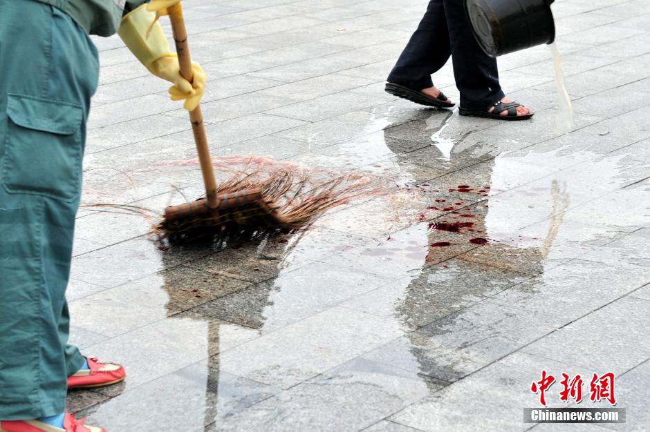 圖為環(huán)衛(wèi)工人在清理案發(fā)地點(diǎn)的血跡。