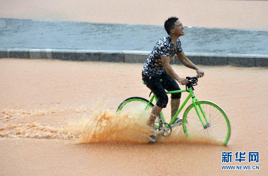 5月11日，一名行人在深圳街頭冒雨騎行。