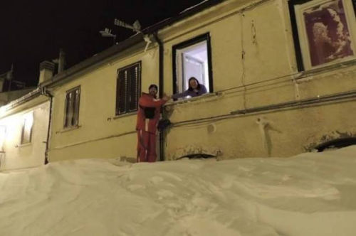 一個居民站在積雪上，可以與一名二樓鄰居在窗口握手。（來源：意大利氣象局）