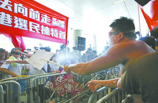 17日，在香港立法會(huì)外，一名反對(duì)政改的男子向支持派人群投擲標(biāo)牌。