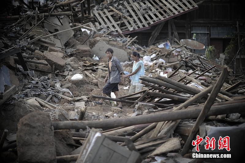 2014年8月5日，云南昭通龍頭山鎮(zhèn)老街，一對(duì)夫妻從居住房屋的廢墟中走過(guò)。