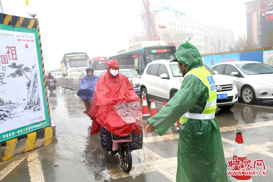 交通協(xié)管員下雨天堅守崗位，疏導交通。