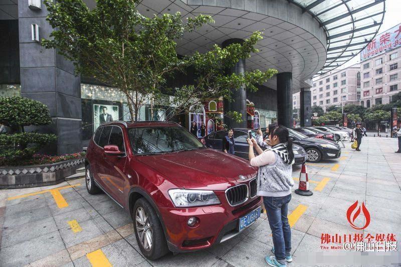 一輛停在停車位上的寶馬轎車，被墜落的樹(shù)枝砸中，樹(shù)枝徑直插入車內(nèi)，現(xiàn)場(chǎng)引發(fā)不少市民圍觀拍照。
