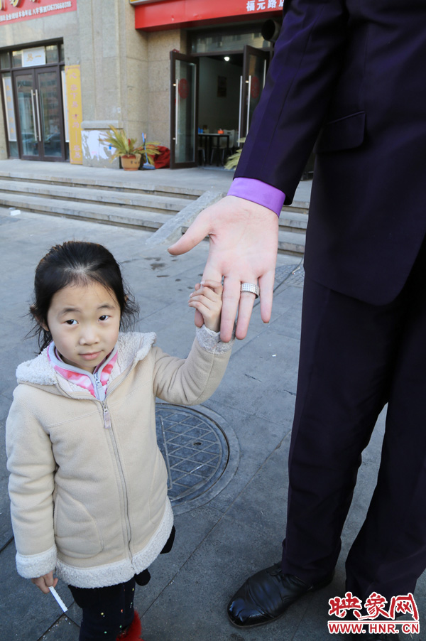 巨人“張歡”牽著一名漂亮的小女孩，兩人的手大小對(duì)比非常明顯。