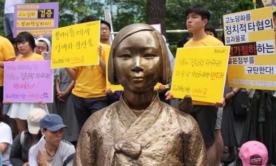 7月2日，在韓國(guó)首爾的日本駐韓國(guó)大使館前，民眾在慰安婦少女像旁手持標(biāo)語(yǔ)參加抗議活動(dòng)。