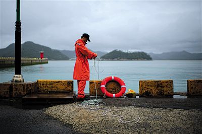 7月6日，韓國珍島，一名海岸警察在港口系救生圈。4月，客輪在珍島近海發(fā)生沉船事故后，仍有11人下落不明。