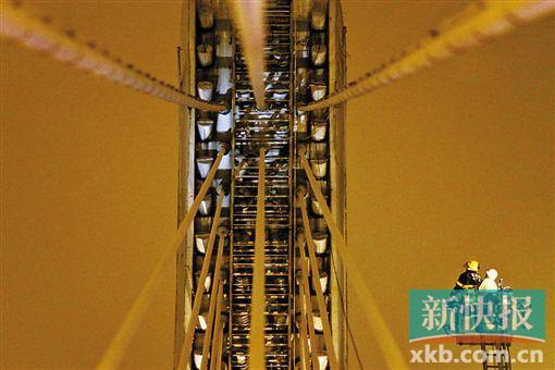 截至今日零時(shí)，男子仍未有下橋舉動(dòng)。圖為公安和消防人員乘消防云梯在高空上和男子交談。