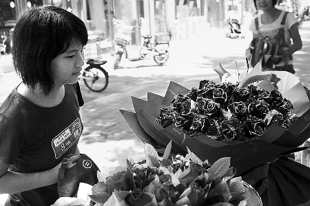 鄭州市農(nóng)業(yè)路一家花店擺放的玫瑰花吸引著一位過往女孩。