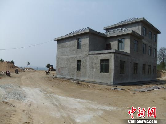 鴨河水庫庫區(qū)邊的新建別墅，一面墻上寫著“拆”，另一邊在加緊施工。吳揚(yáng)　攝
