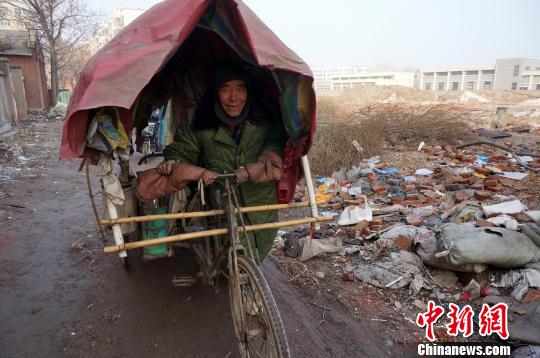 圖為老人走出窩棚，推著三輪車準(zhǔn)備出去撿拾廢品。周小云 攝